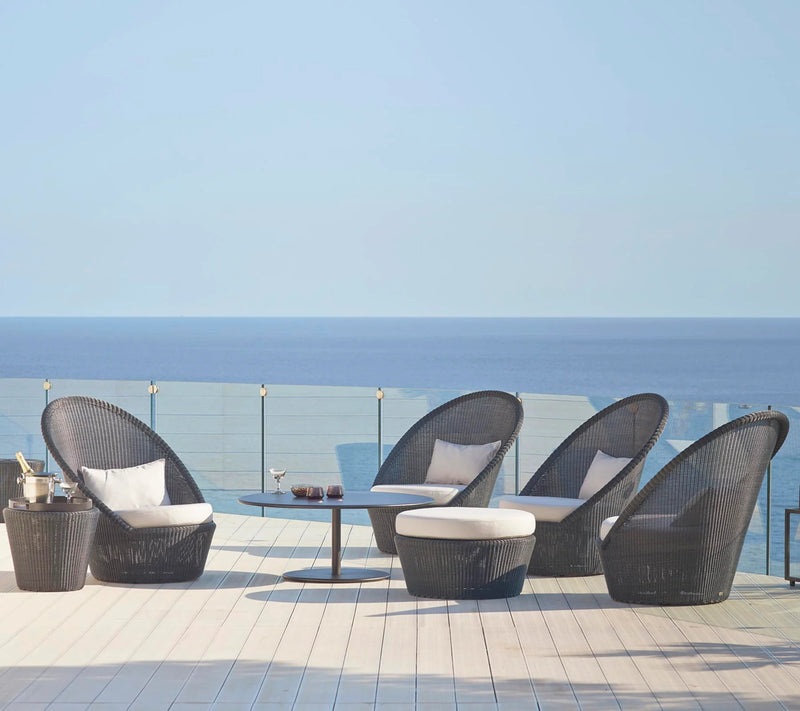 Set of four black armchairs with a matching footstool next to the ocean