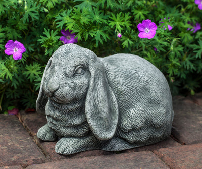 Light gray bunny with long ears sitting in front of pink flowers