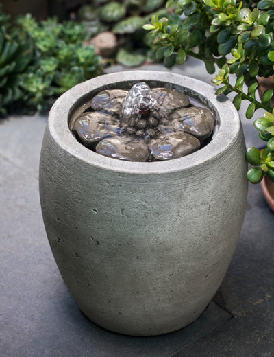 Tabletop fountain with camellia design on top pictured on gray floor