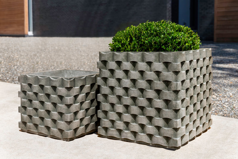 Two square containers with weave pattern shown in front of gravel courtyard