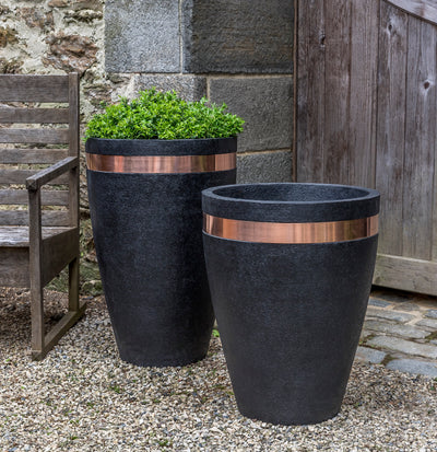 Set of 2 black containers with a copper band at the top show next to a wooden chair