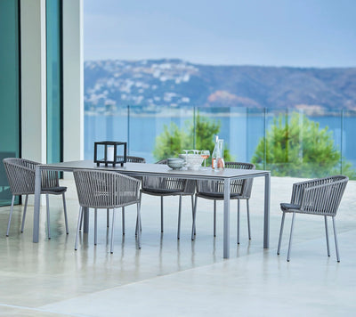 Grey dining set with rectangular table and matching chairs with water view in the background