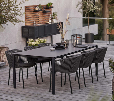 Rectangular dining table with matching chairs in front of outdoor kitchen
