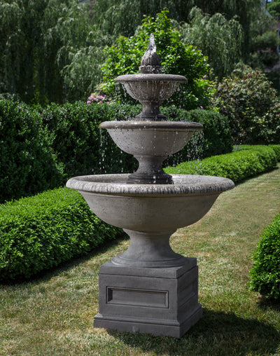 Three tiered fountain with large bowls shown running in front of boxwood hedge
