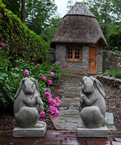 Two rabbits facing each other in front of a little hut