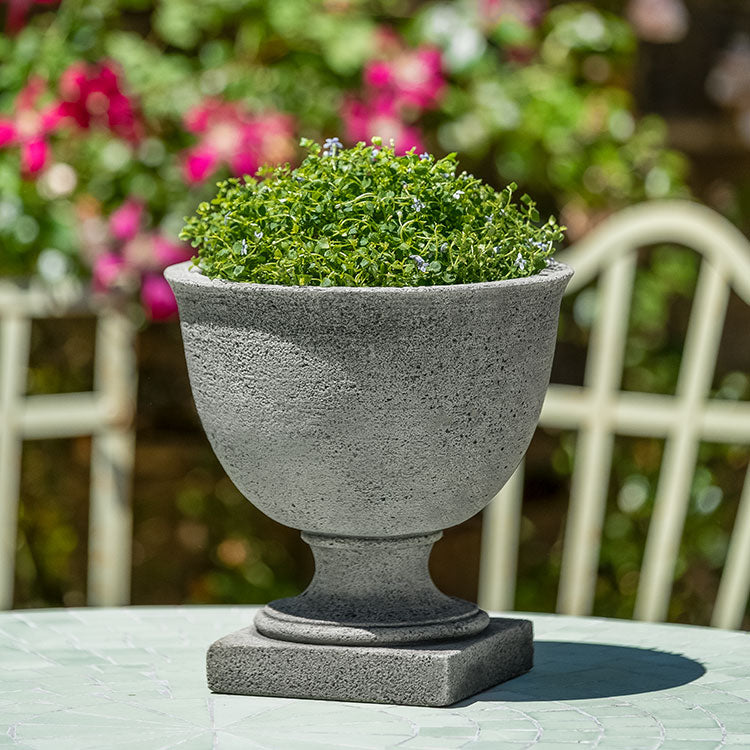Small urn shown on top of table and planted with moss