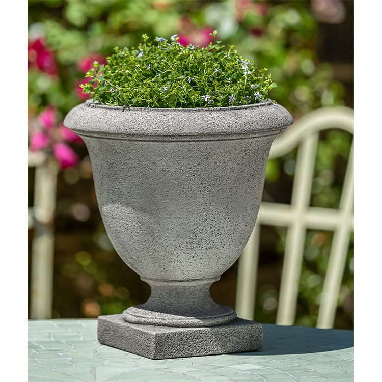 Small urn planted with greenery in front of pink blooms