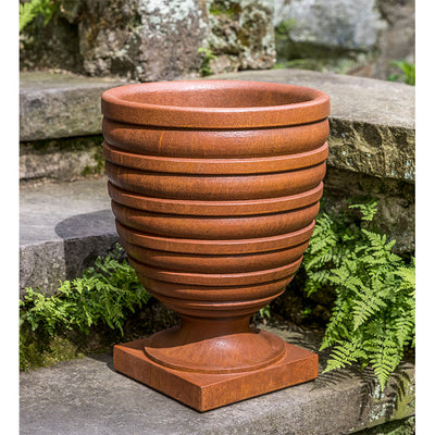 Ribbed urn shown on grey steps with ferns