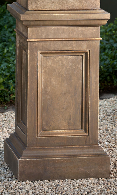 Brown square pedestal shown on gravel ground