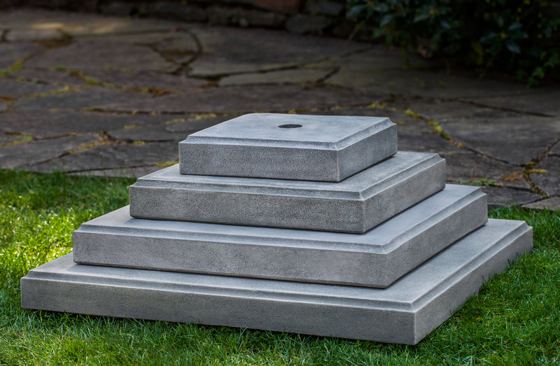 Four stacked square plinths shown on lawn