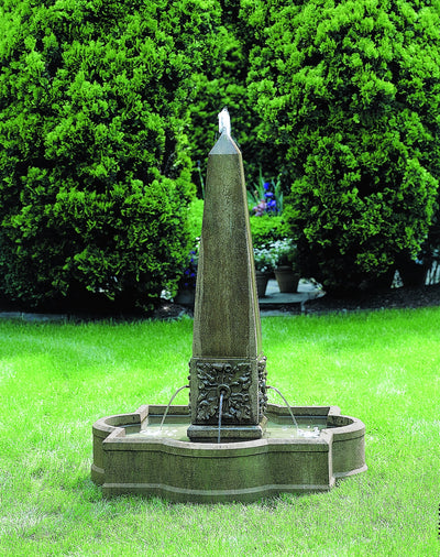 In basin fountain with obelisk in the center  shown running in front of trees