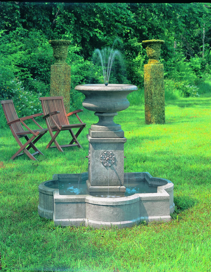 Fountain pictured on grass with two garden chairs in the background