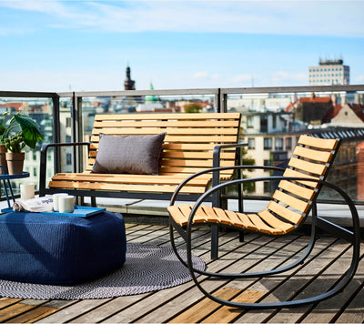Wood and metal bench and rocking chair on rooftop terrace with city views