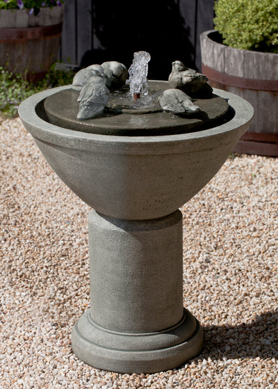 Bird bath fountain with birds sitting on top part pictured on gravel