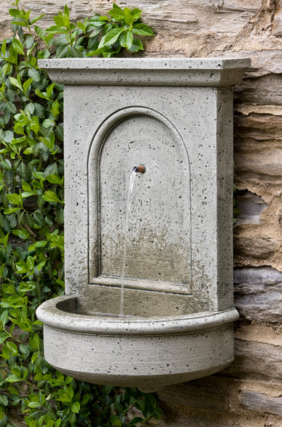 wall mounted fountain with one spout pictured against rock wall