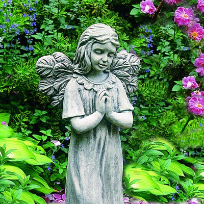 Close up of praying angel in front of greenery and blooms