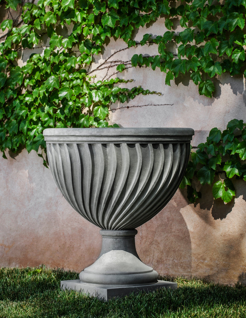 Grey urn shown against an ivy wall