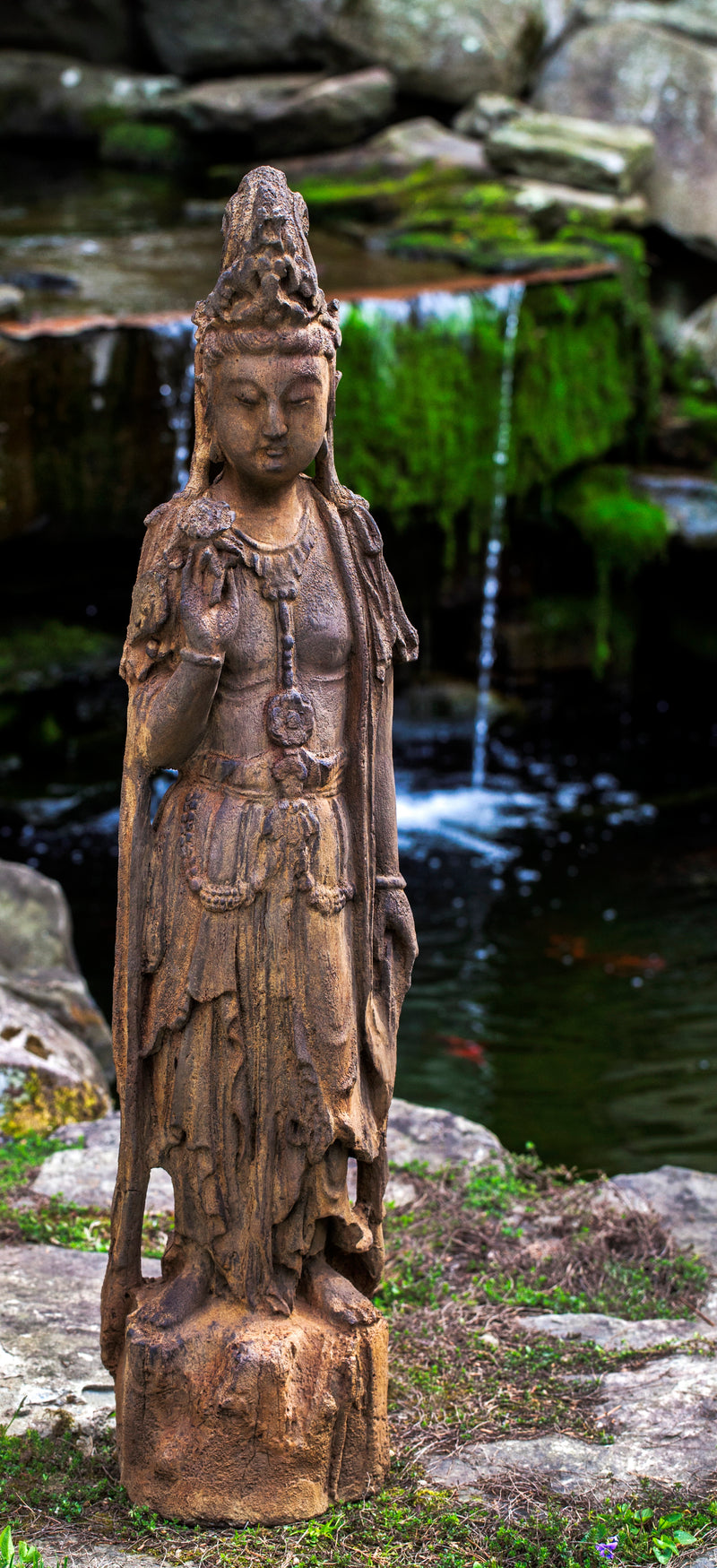 Quan Yin standing on small plinth in front of water
