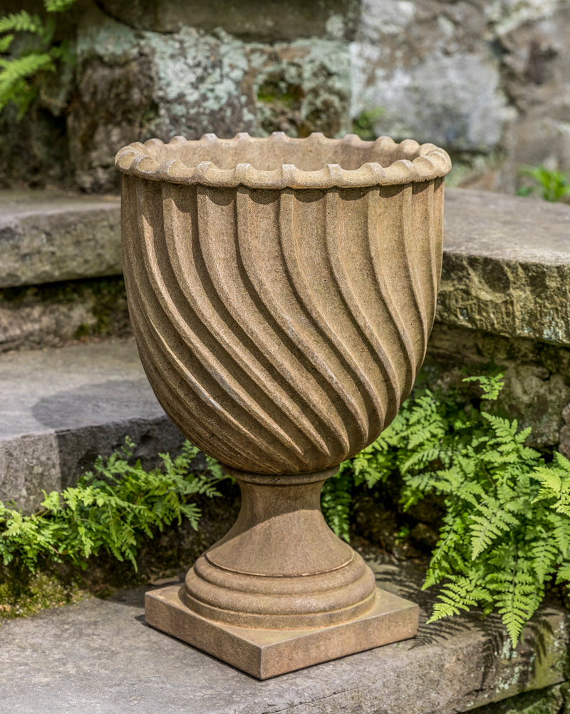 Small light brown urn shown on steps next to ferns