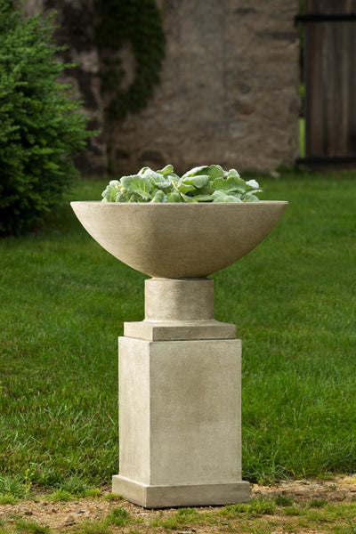 Square pedestal shown with an urn in front of lawn area