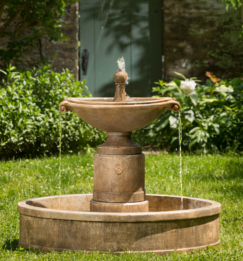 Light brown fountain with oval top bowl spilling water on both ends into round basin 