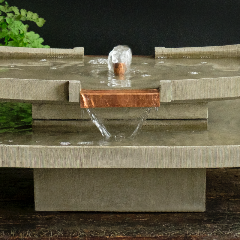 Detail picture of table top fountain with flat copper spout spilling water into lower bowl