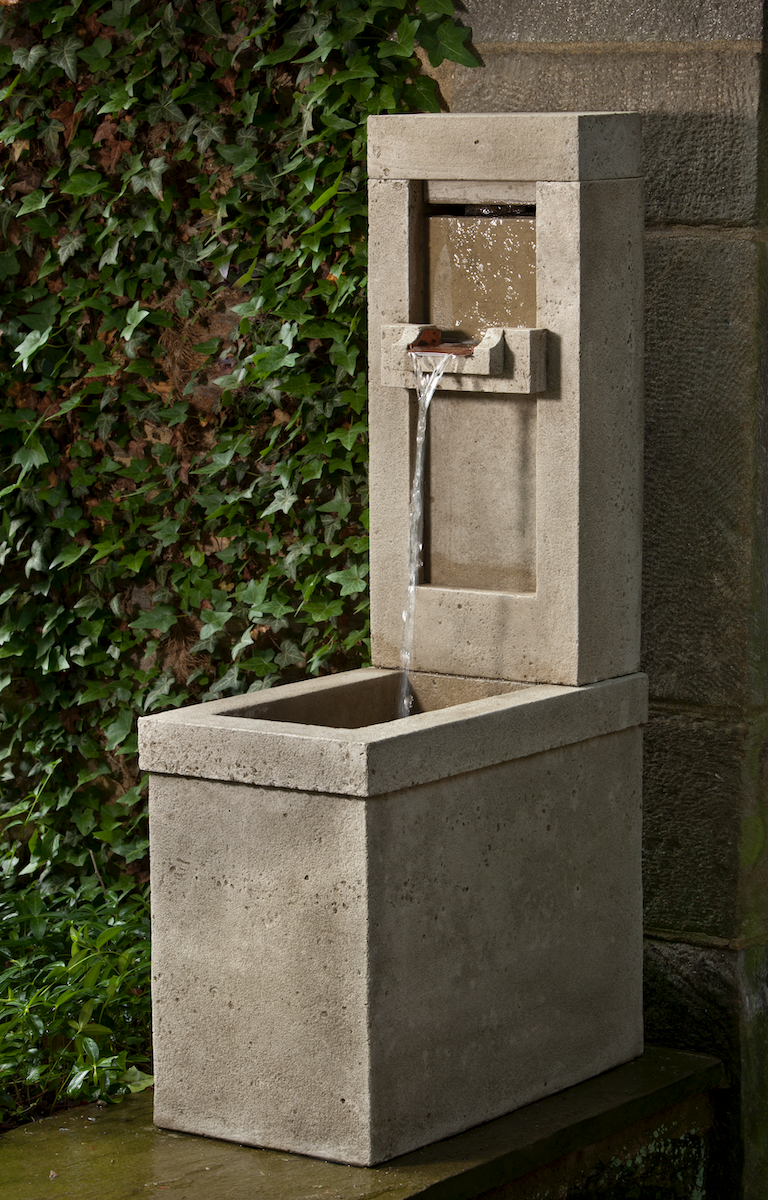 Rectangular wall fountain in grey finish on top of wall and next to ivy wall
