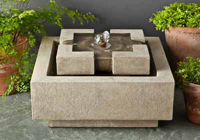 Square tabletop fountain pictured with planted terra cotta pots