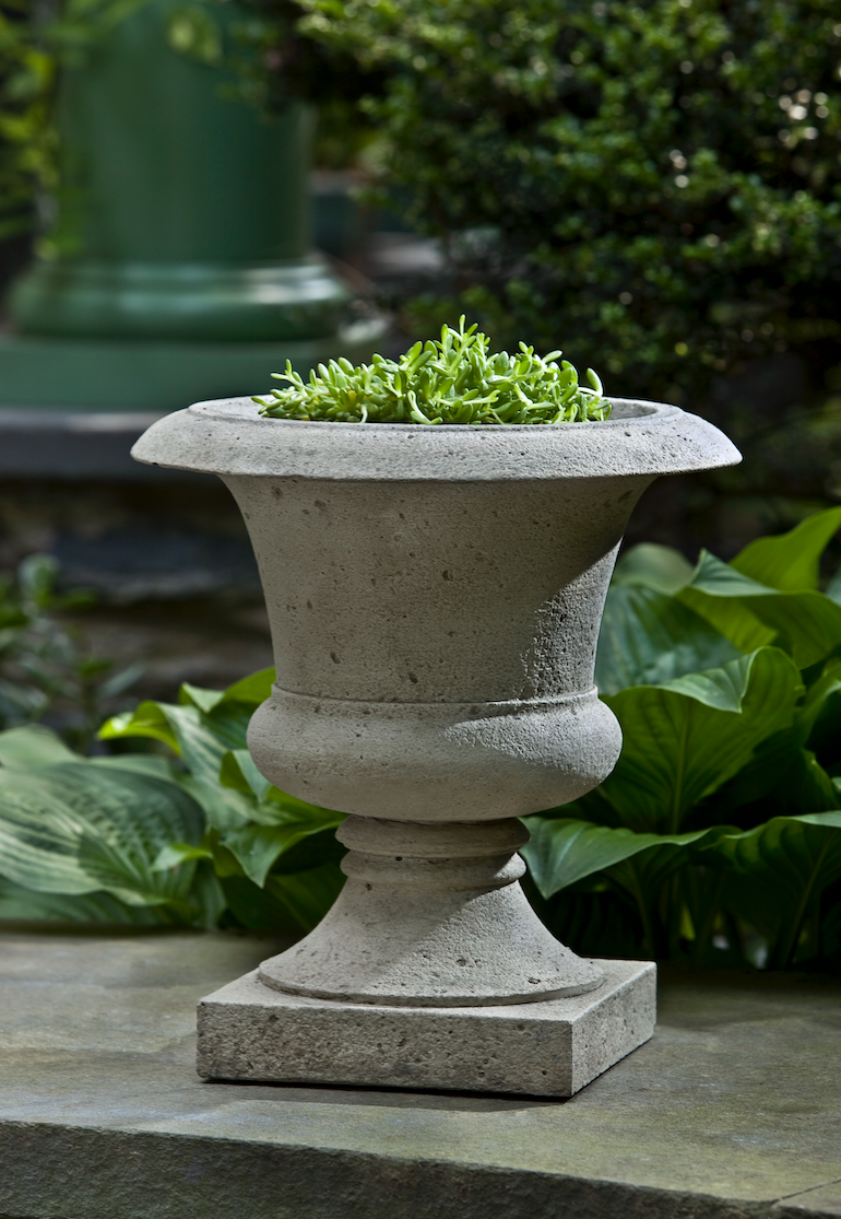 Grey urn on top of wall in front of green pillar