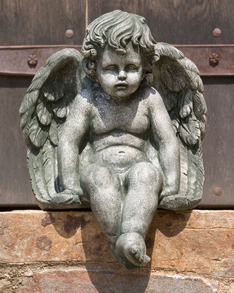 Cherub sitting on a stone wall with hands on sides