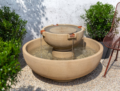 Round basin and round tiered top with four copper spouts pictured next to boxwood shrubs