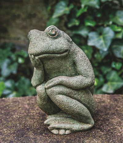 Light green frog sitting with one foot on top of the other and holding head up with hand