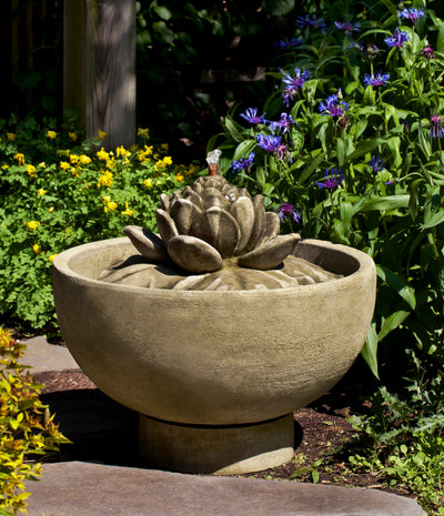 Round basin fountain with lotus flower shaped center and copper spout pictured in front of flowers