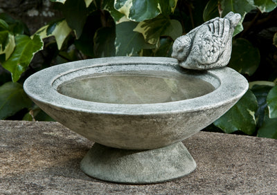 Round gray birdbath with concrete bird perched on edge