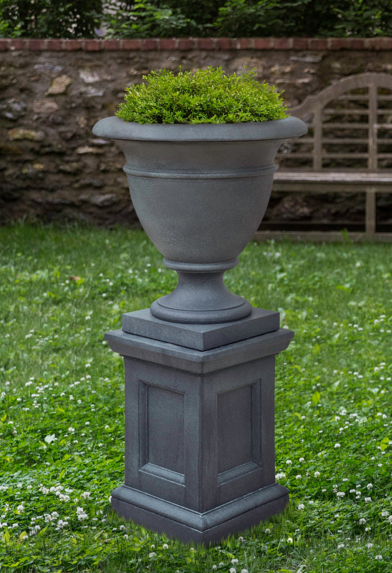 Grey urn planted with greenery shown on a pedestal