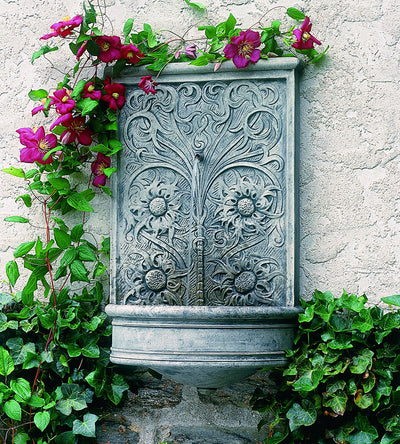 Wall fountain with floral design hanging on wall with clematis flowers