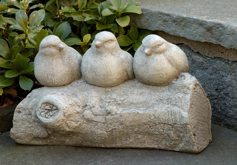 Three light gray birds sitting on a log