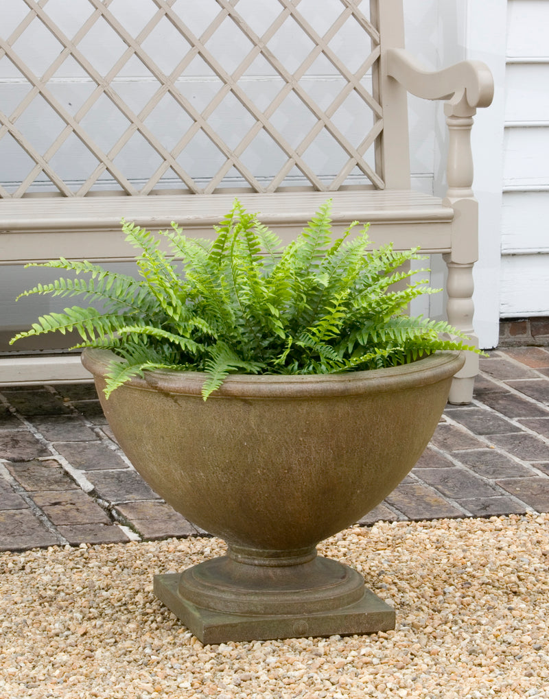 Classic urn planted with ferns in front of a wooden bench