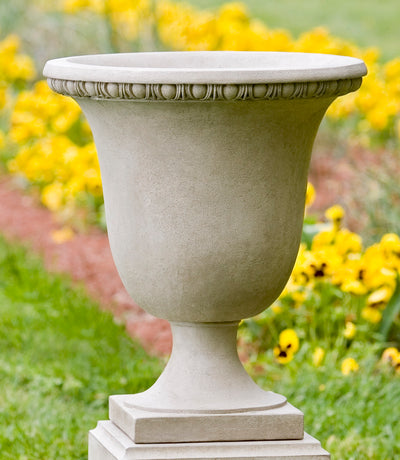 Egg and dart urn shown in front of yellow pansies