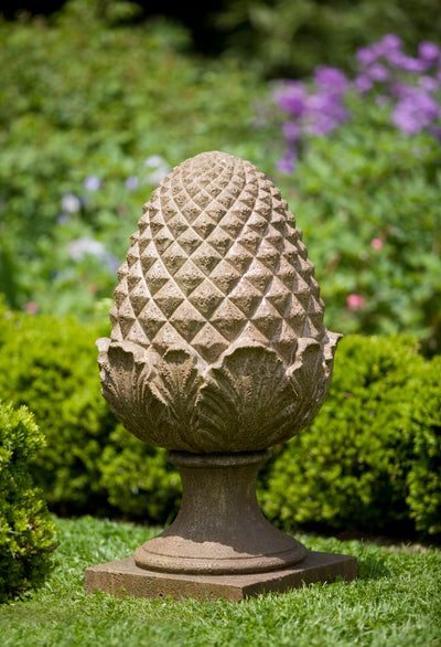 Light brown pineapple shaped finial sitting on grass