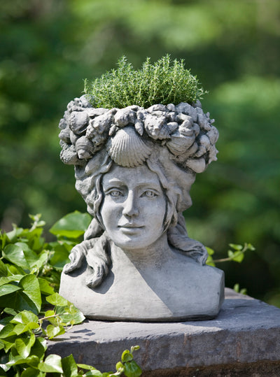 Woman's face shaped urn planted with herbs on top of a column