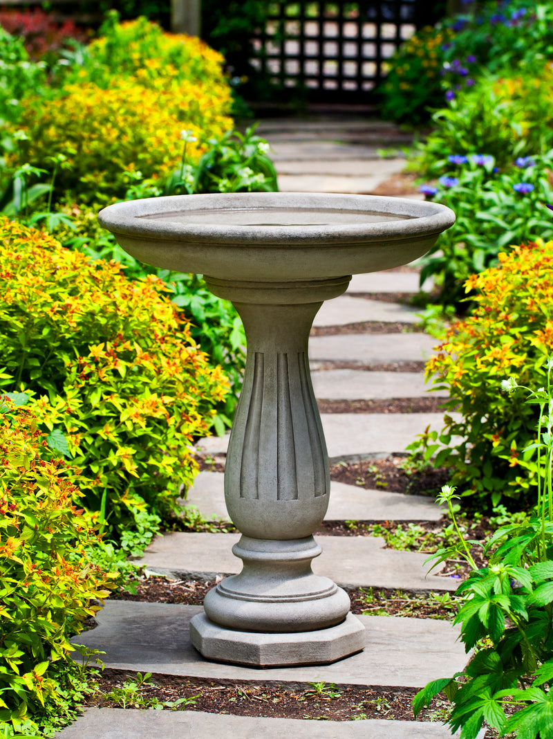 Classic gray birdbath with round bowl and etched straight lines on curved pedestal