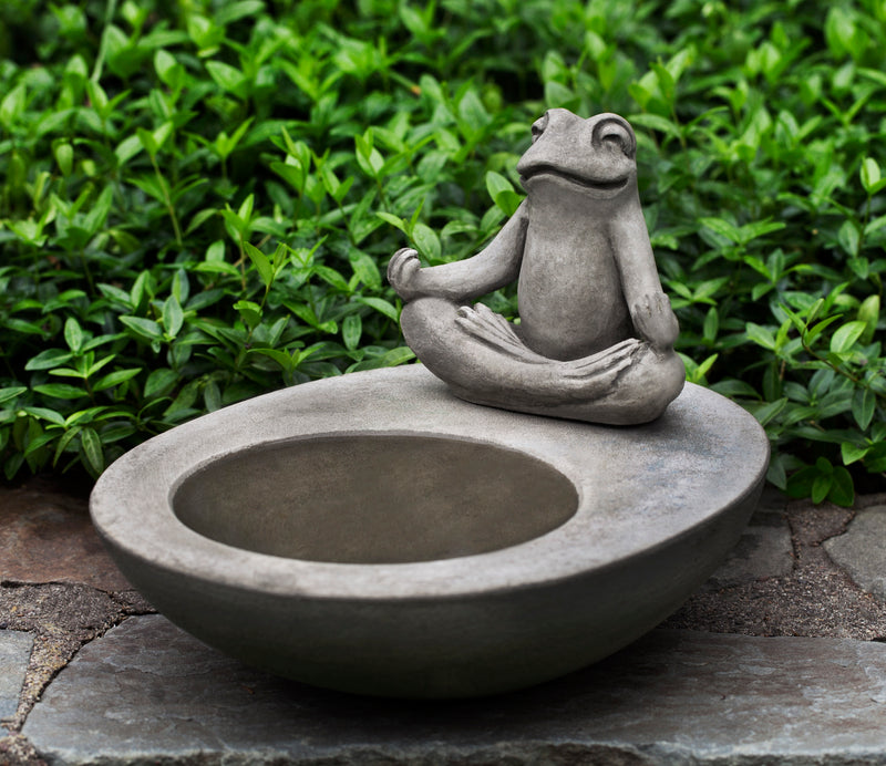 Small gray birdbath with zen frog sitting on side in a yoga pose