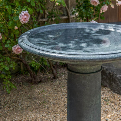 Slate gray birdbath bowl detail in front of rose shrub