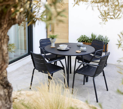 Black dining metal set shown on gray patio with grass in the forefront