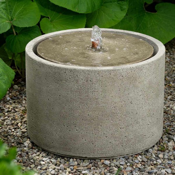 Round fountain with circular top and copper spout pictured on gravel