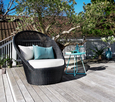 High back armchair shown on a gray deck with tree in the background