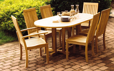 Oval teak dining table shown with six chairs on brick patio