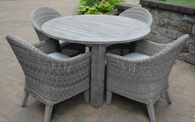 Weathered teak round table with four armchairs  on paver patio
