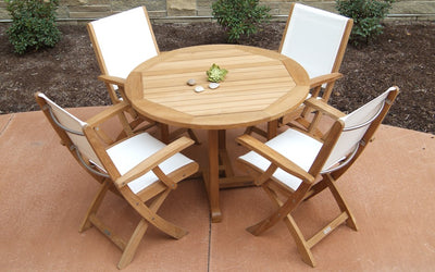 Teak dining set with round table and four white chairs shown on reddish patio